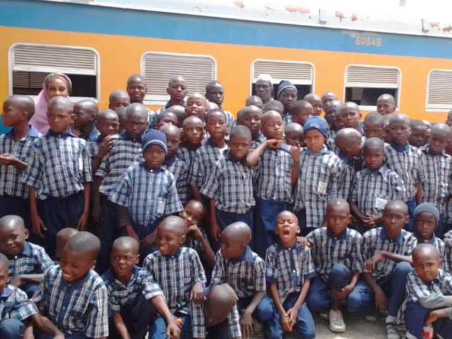 Pupils in school uniform gathered beside a passenger train on a school trip
