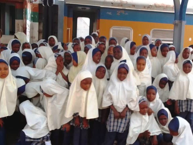 Pupils in white hijabs gathered beside the train on the same school trip