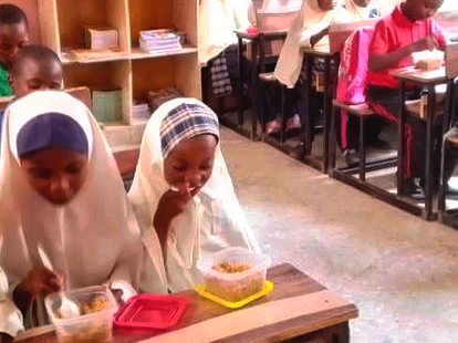 Pupils eating lunch from lunch boxes at their desks in a classroom